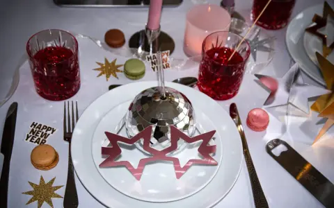 Enkel nyårsdukning med disco-boll, stjärnor, macarons och röda drinkar. En festlig och glittrig bordsdekoration för att fira in det nya året.