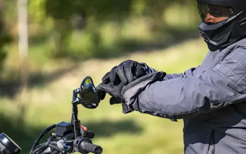 Motociclista con casco integrale obbligatorio e guanti neri, pronto per un viaggio su strada.