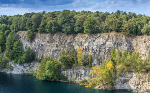 Skałki Twardowskiego w Krakowie, z malowniczym kamieniołomem i turkusową wodą, otoczone bujną zielenią drzew.