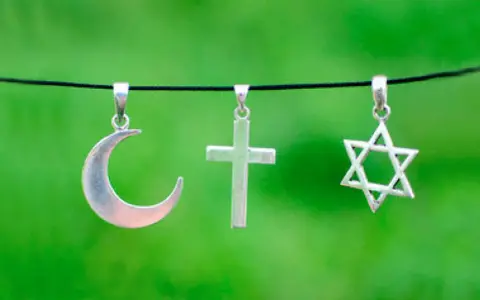 Srebrny półksiężyc, krzyż i gwiazda Dawida wiszą obok siebie. Symbolika islamu, chrześcijaństwa i judaizmu w harmonii.