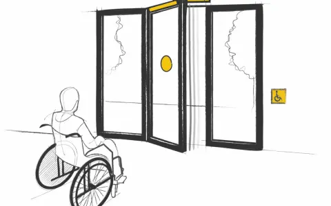 Persona en silla de ruedas se acerca a puertas automáticas, cumpliendo la normativa de puertas de portales para accesibilidad.