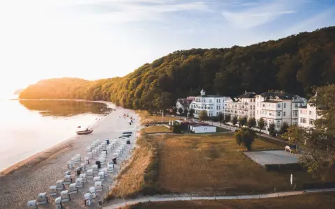 Sonnenuntergang am Binz Strand mit vielen Strandkörben, weißen Villen und einem dichten Wald.