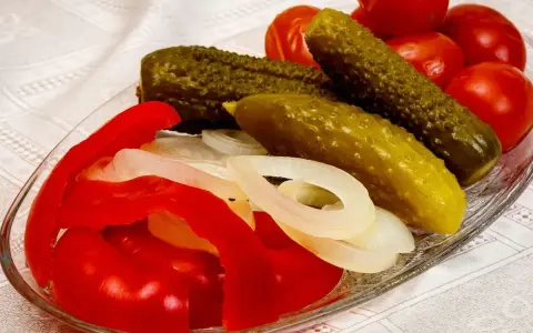 Ogórki, pomidory, papryka i cebula na talerzu.