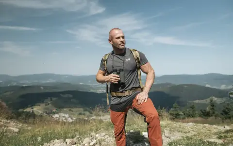 Mężczyzna w letnim stroju górskim: koszulka, spodnie trekkingowe i plecak. Idealny przykład, jak się ubrać w góry latem.