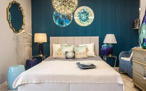 Złote, ozdobne lustro w sypialni feng shui odbija niebieską ścianę i dekoracje.