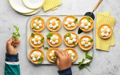 Douces tartelettes à l'abricot, décorées de crème fouettée et de menthe, prêtes à être dégustées.