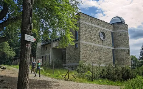 Obserwatorium astronomiczne na Lubomirze, kamienny budynek z kopułą, obok szlak turystyczny.