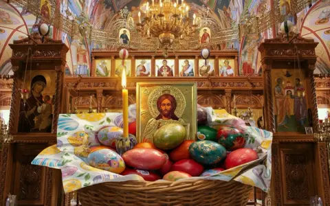 A basket of colorful Easter eggs sits before an icon of Jesus in a richly decorated church, hinting at when Easter is celebrated in Europe.