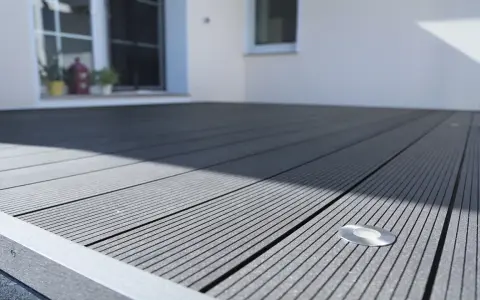 Moderne Terrasse mit grauen WPC Terrassendielen verlegen. Ein kleiner Bodenspot ist integriert.