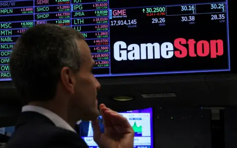 Un hombre observa la pantalla de cotizaciones de GameStop, analizando la previsión de fondos y el comportamiento del mercado.