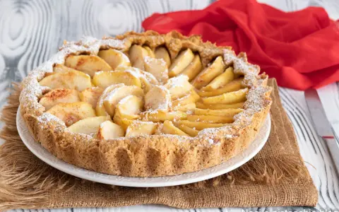 Una deliziosa crostata di mele, con mele a fette disposte a raggiera e spolverata di zucchero a velo.