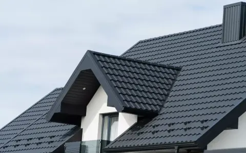 Nowy, ciemnoszary dach z blachodachówki. Zastanawiasz się nad wymiana dachu cena? Sprawdź, jak nowoczesne pokrycie wpływa na wygląd domu.