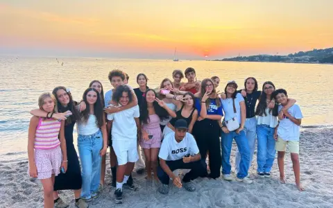 Groupe d'adolescents souriants sur une plage corse au coucher du soleil.