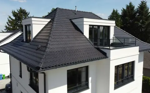 Modernes Haus mit dunkler Dachbeschichtung. Mögliche Nachteile der Dachbeschichtung: Hitzestau im Sommer, höhere Kosten bei Reparaturen.