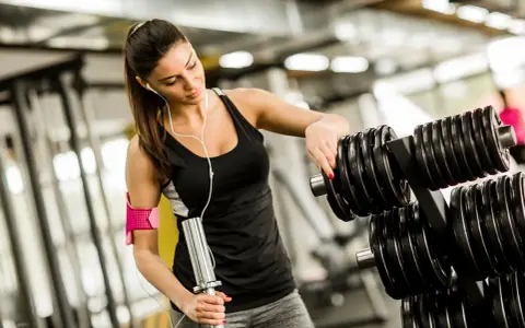 Kvinna väljer vikter på gymmet, bra gym tips för din träning.