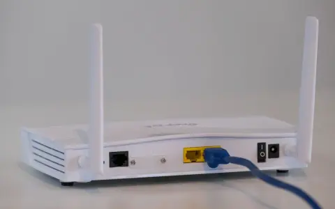 Biały modem z dwiema antenkami, podłączony niebieskim kablem Ethernet. To urządzenie, które pozwala na połączenie z internetem.