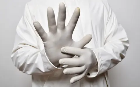 Dłonie w białych rękawiczkach jednorazowych, gotowe do pracy. Różne rodzaje rękawiczek jednorazowych zapewniają ochronę.