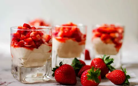 Enkel dessert med jordgubbar i glas, toppad med färska jordgubbar och en krämig fyllning. Perfekt för en sommardag.