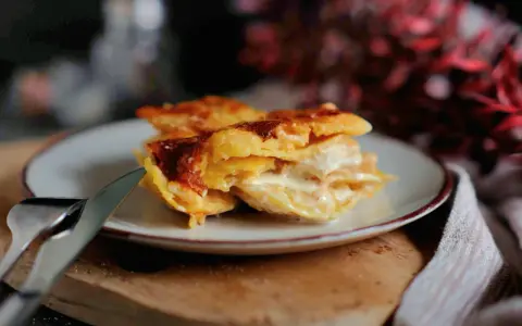 Ein Stück cremiges Kartoffelgratin mit goldbrauner Kruste auf einem Teller, bereit zum Servieren. Dieses Kartoffelgratin Rezept ist ein Genuss!