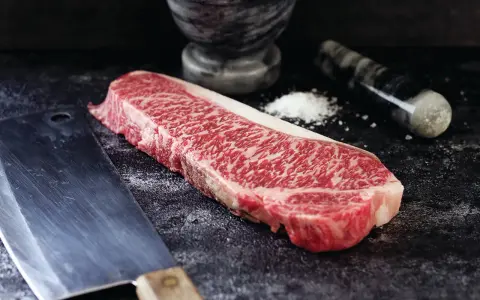 Wyjątkowy stek z krowy wagyu, gotowy do przygotowania. Obok nóż i moździerz z solą.