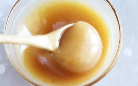 En sked lyfter krämig kolasås ur en skål. Perfekt för ditt kolasås recept!