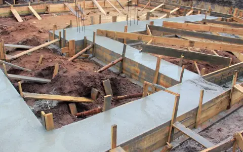 Budowa fundamentów: świeży beton i drewniane szalunki pokazują, jak połączyć stary fundament z nowym.