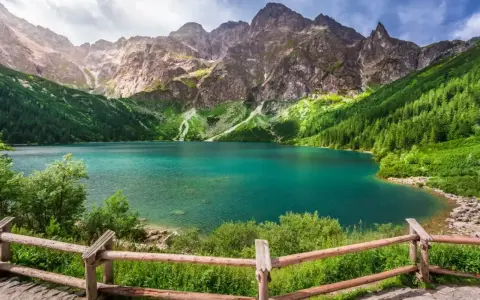 Turkusowe jezioro otoczone zielonymi zboczami gór, przypominające beskidzkie Morskie Oko.