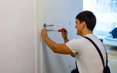 Hombre arregla manija de puerta con destornillador. Podría estar a punto de cambiar marco puerta.