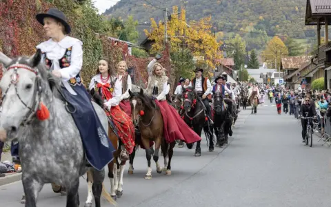 Redyk Szczawnica w barwnych strojach ludowych na koniach, w tle jesienne wzgórza i tłum widzów.