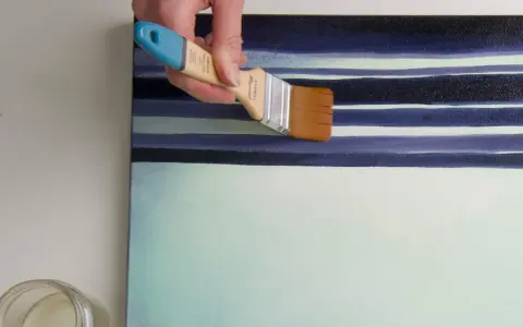 Main d'artiste appliquant une couche de vernis sur une toile aux rayures bleues et blanches. Quel vernis !