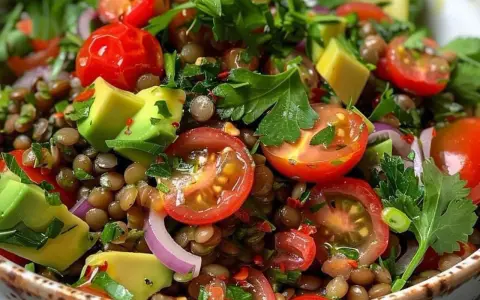 Fresca insalata di lenticchie estiva con pomodorini, avocado, cipolla rossa e prezzemolo.