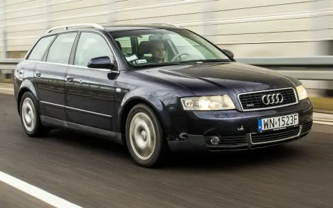 Ciemnogranatowe Audi B6 Avant pędzi autostradą. Kierowca skupiony na drodze.