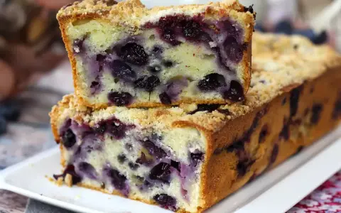 Saftiger Heidelbeerkuchen mit Streuseln, ein Stück gestapelt auf dem ganzen Kuchen. Köstlich!