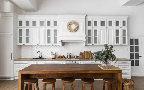 Cuisine lumineuse avec des armoires blanches et un îlot en bois massif. On dirait qu'on a réussi à faire une cuisine avec des vieux meubles, le tout dans un style rustique chic.