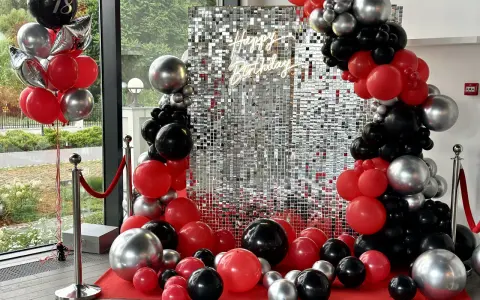 Błyszcząca ścianka z cekinami i girlandy z czerwonych, czarnych i srebrnych balonów na 18 urodziny.