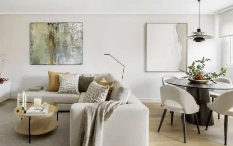 Salones con colores neutros: sofá beige, mesa de centro de madera, cuadros abstractos y mesa de comedor con sillas tapizadas.