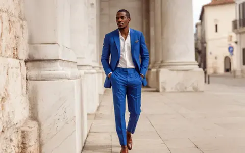 Uomo elegante con abito blu cerimonia, camicia bianca e scarpe marroni. Gli accessori completano il look.