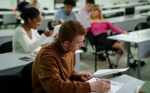 Studenci w sali wykładowej, skupieni na nauce. To dowód, że studia bez matury są możliwe i otwierają drzwi do wiedzy.