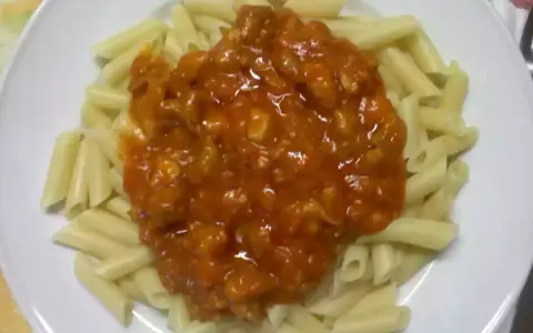 Macarrones con pollo en salsa roja, un plato casero listo para disfrutar.