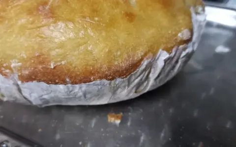Goldbrauner Teig klebt am Backpapier, das auf einem Metallblech liegt. Ein Teil des Teigs ist bereits abgelöst.
