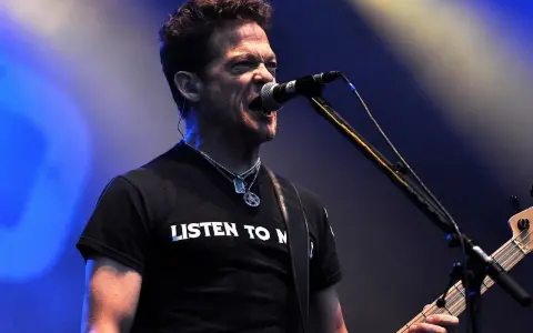 Jason Newsted z zespołu, w czarnej koszulce z napisem "LISTEN TO N", śpiewa do mikrofonu, grając na basie.
