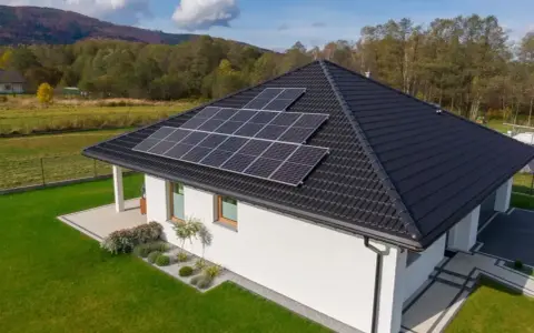 Nowoczesny dom jednorodzinny z panelami słonecznymi na dachu. Obniżone miesięczne zużycie prądu dzięki odnawialnym źródłom energii.