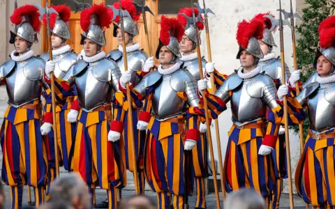 Guardie svizzere in divisa storica, con elmi piumati e alabarde, pronti a difendere la Città del Vaticano.