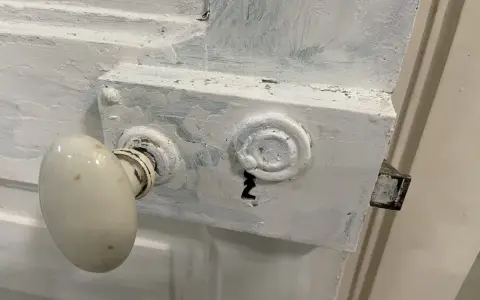 Poignée de porte ancienne et serrure en cours de préparation pour décaper une porte en bois peinte.