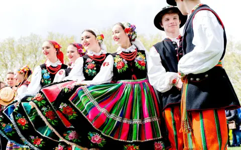 Młodzi ludzie w barwnych strojach ludowych, gotowi do wykonania polskich tańców narodowych.