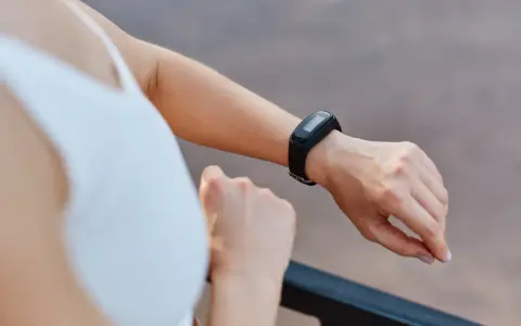 Kobieta sprawdza na swoim nadgarstku, co to jest smartband, monitorując aktywność fizyczną.