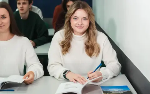 Uśmiechnięta studentka pisze w zeszycie, idealne zdjęcie do legitymacji.