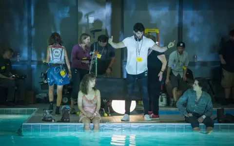 Reżyser instruuje aktorkę siedzącą w basenie. Wszyscy są **trzy kroki od siebie**, tworząc scenę filmową.