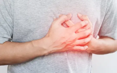 Dłoń na klatce piersiowej, odczuwając niepokojące kołatanie serca w nocy.