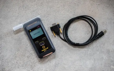 Alkomat z ustnikiem i kablem USB na szarym tle.
